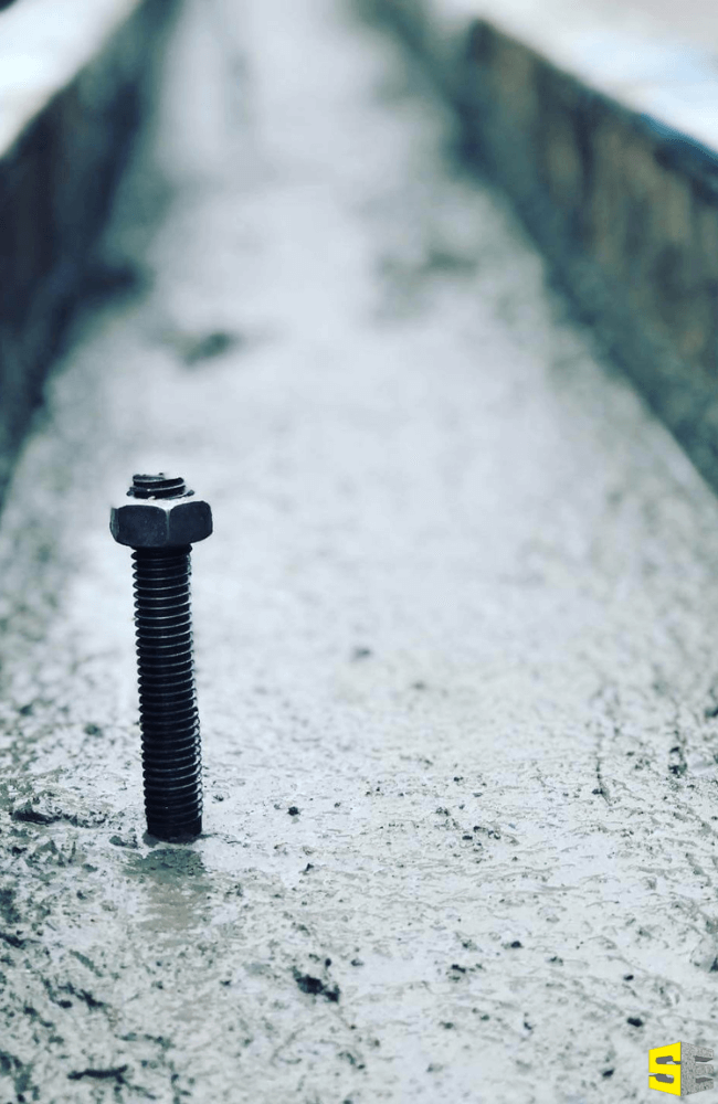 A screw sticking up out of freshly poured concrete