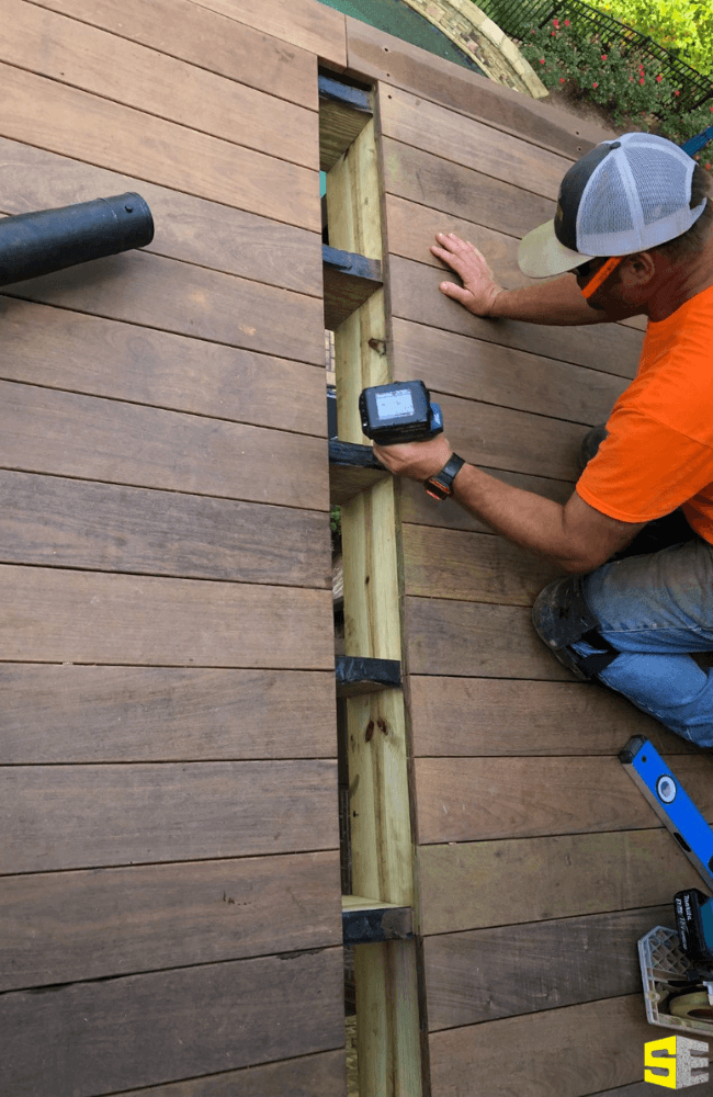 A person measuring out the wood for an outdoor piece