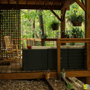 Custom built patio with outdoor sofa and wooden rocking chair situated in a green forest.