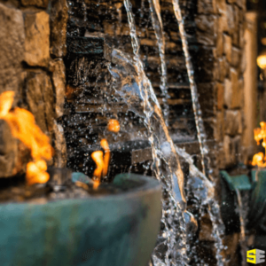 Close up of an outdoor stone water feature with fire lighting on the sides