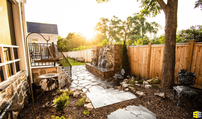 Outdoor backyard of a residential home with a water feature backed up onto a wooden fence