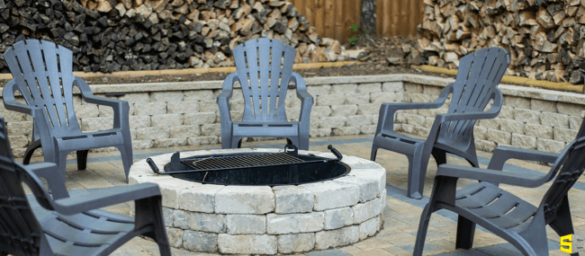 A bonfire area with stone hardscaping for the firepit and the surrounding walls