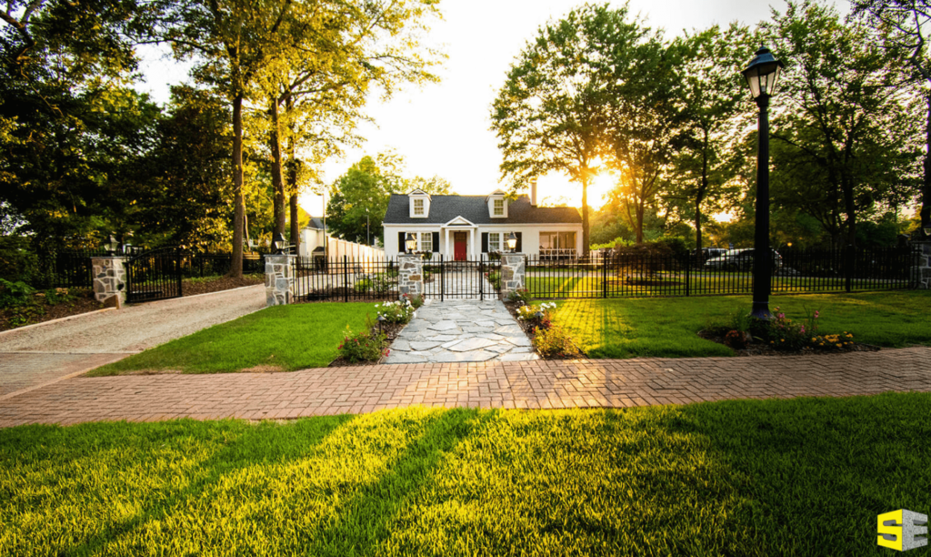 An image of a residential home, the sun rising in the background highlighting the beautifully done yard