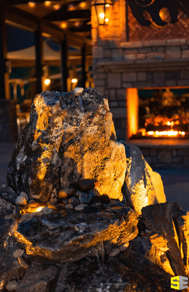 A close up image of lighting for a rock, a fireplace in the background