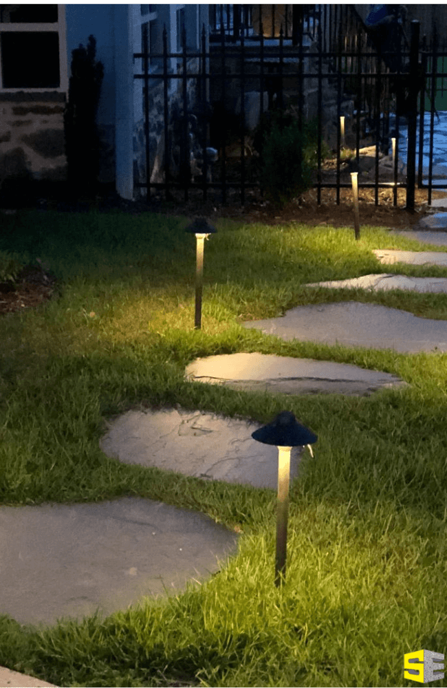 Small mushroom lights illuminating a small path to a residential home