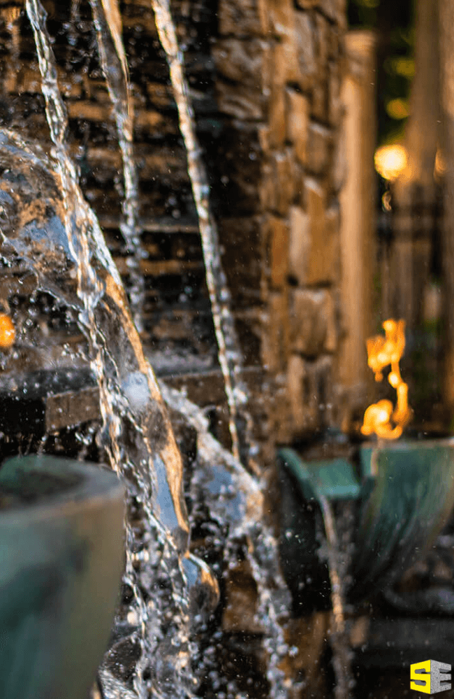 A water feature with fire outdoor lighting in the background