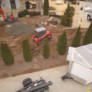 A tractor, working to smooth out a construction area by removing the loose dirt from the top