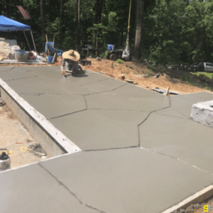 Freshly poured concrete, being smoothed out by a construction worker