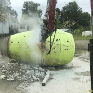 A large machine cutting into a green concrete mass