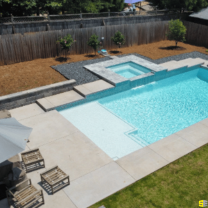 The finished product on an inground pool, with concrete walkways and a concrete water feature