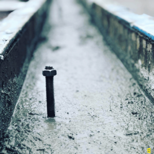 A screw with a washer on top, left to stand in drying concrete