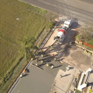 An overhead shot of a construction site, with a concrete truck pouring concrete onto a site full of workers