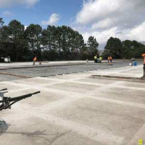 A drying concrete construction site with workers in the background