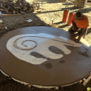 A worker smoothing out a 2D concrete carving of a bear