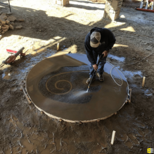 A worker power washing a 2D carving of a bear