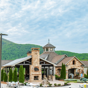 A picturesque view of a large gazebo area attached to a stone building, a stone built fireplace with a concrete carved bear on the hearth