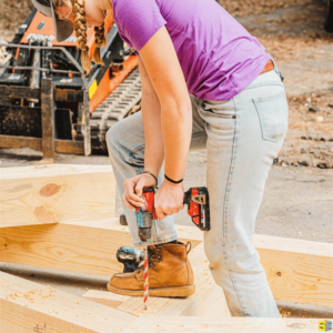 A Straight Edge worker using a drill with a large attachment to create holes in the frame