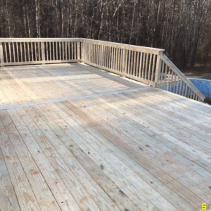 A wooden deck, freshly built, with steps leading to an outdoor pool