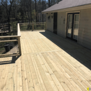 A wooden deck, freshly built, attached to the second floor of a residential home