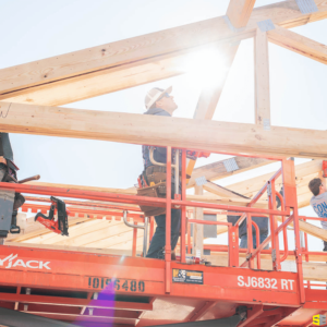 A construction worker piecing the frame of an outdoor gazebo together while standing on a lift