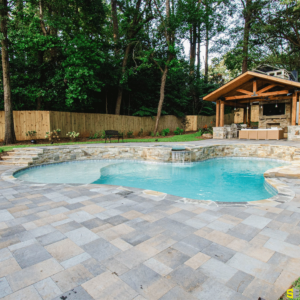 A focus on the concrete work surrounding an outdoor pool with a wooden outdoor gazebo in the background