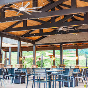 A picture focusing on the carpentry of the ceiling of an outdoor gazebo, plenty of outdoor seating underneath it