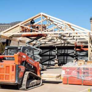 A picture with a lift, a worker connecting pieces of the frame of an outdoor gazebo