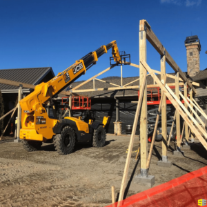 A crane used to prop up the beginnings of an outdoor gazebo frame