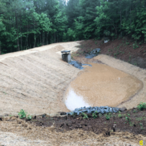 Finished product of a man made draining area to the side of a dirt road