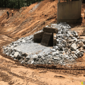 A man made drainage system, surrounded by large rocks