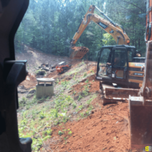 A crane, surrounded by other construction vehicles, digging out a hole for a project