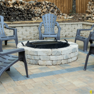 A fire pit surrounded by short retaining walls and a concrete fire place in the center