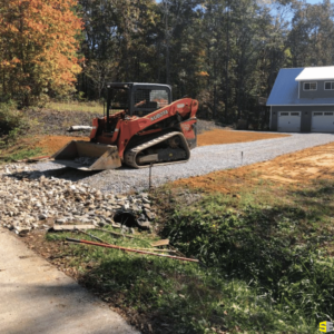 A tractor moving gravel to flatten a residential driveway