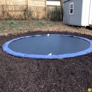 An in ground trampoline freshly landscaped into a residential backyard