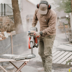 A worker, using an electric saw to cut a piece of stone