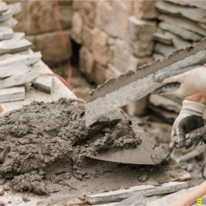 A worker pouring fresh concrete onto a retaining wall