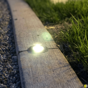 A close up of an inground light in a concrete walkway