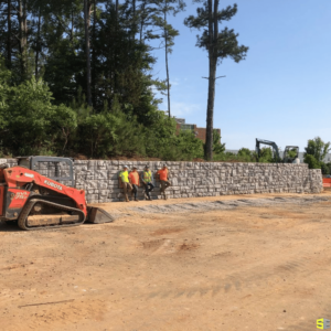 Four workers leaning against a retaining wall that has been freshly built