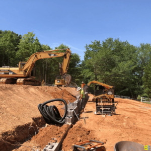 A couple of workers using a couple of cranes to build a stone retaining wall