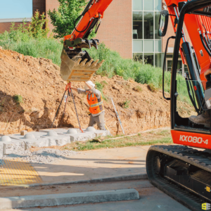 A worker using the help of a crane to lay the foundation of a retaining wall